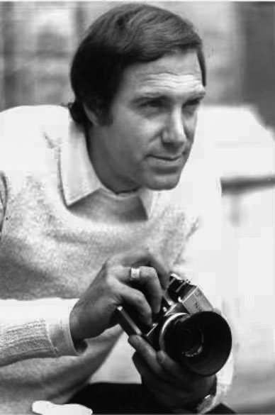 Black-and-white photo of a man photographer holding a camera, looking focused and ready to shoot.