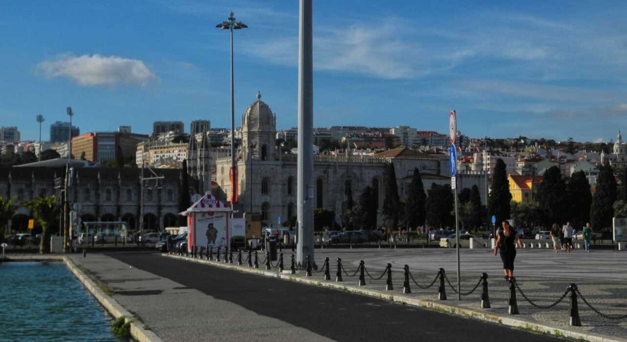 Lungomare di Belém a Lisbona con il Monastero dos Jerónimos sullo sfondo, persone che passeggiano e vista sul mare