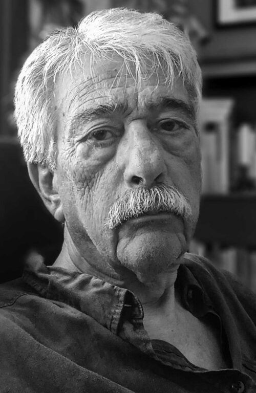 Black-and-white close-up portrait of an elderly man with white hair and mustache.